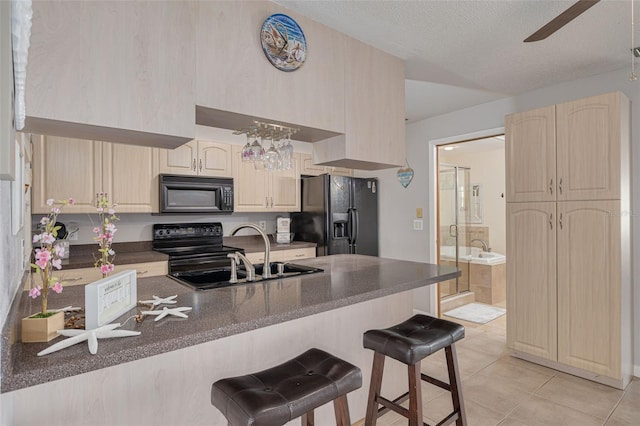 2605 Fulton St SW, Largo, FL 33774 - kitchen featuring black appliances, a sink, dark countertops, a breakfast bar, and light brown cabinets