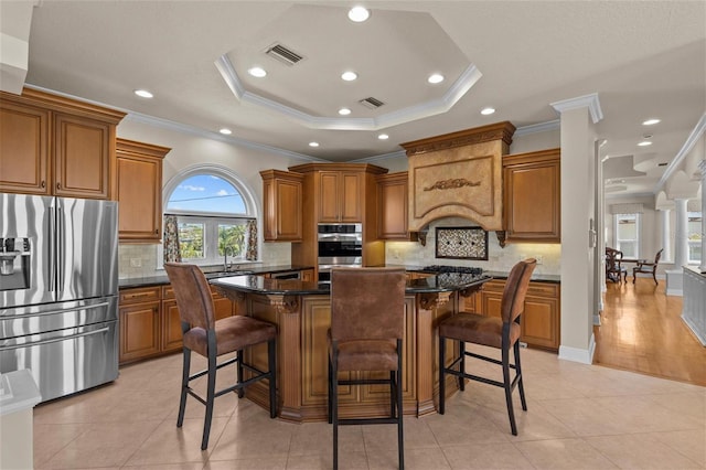 kitchen with appliances with stainless steel finishes, brown cabinets, a tray ceiling, and visible vents