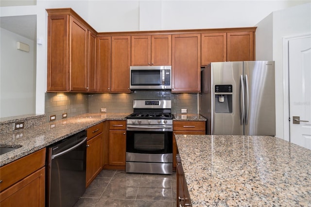 5331 Villagebrook Dr, Wesley Chapel, FL 33544 - kitchen featuring appliances with stainless steel finishes, light stone countertops, brown cabinetry, and decorative backsplash