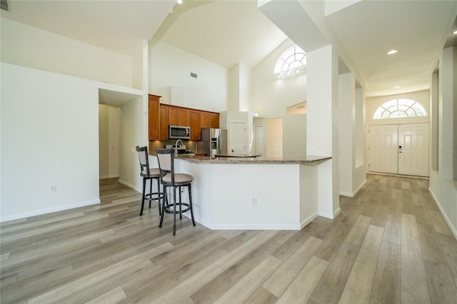 5331 Villagebrook Dr, Wesley Chapel, FL 33544 - kitchen with stainless steel appliances, light wood-style flooring, brown cabinetry, stone counters, and a kitchen breakfast bar