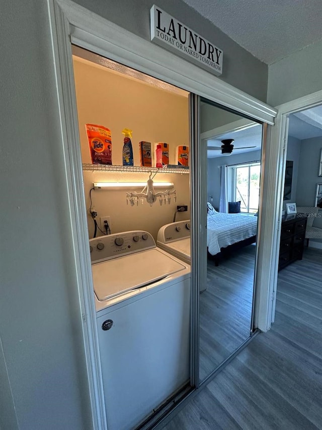 washroom featuring a textured ceiling, washer and clothes dryer, laundry area, and wood finished floors