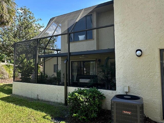 back of property featuring central AC, a lanai, and stucco siding