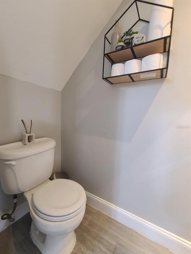 bathroom with toilet, baseboards, vaulted ceiling, and wood finished floors