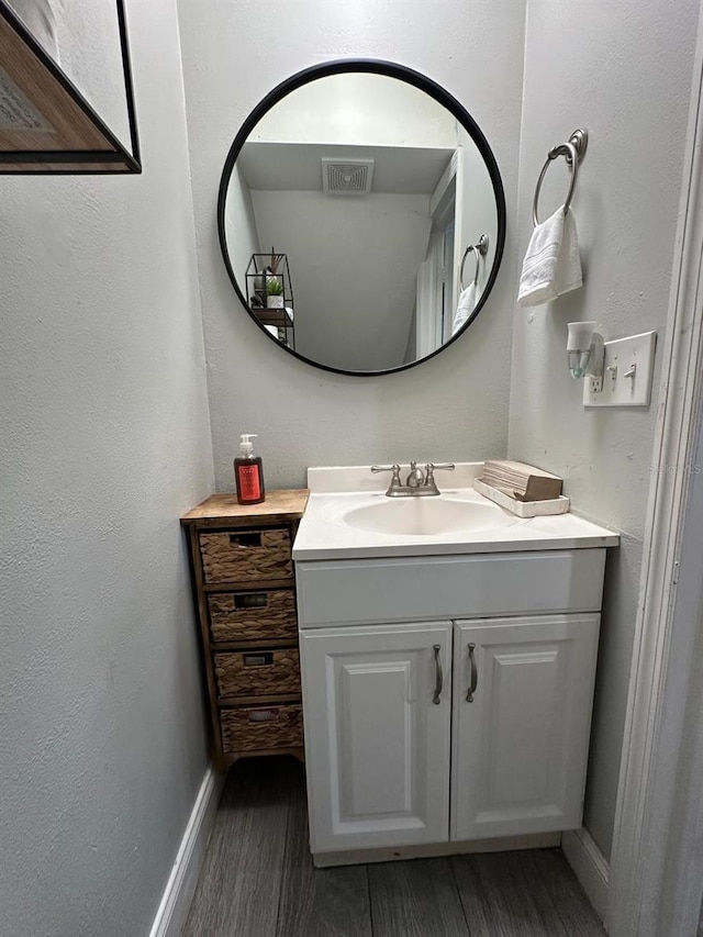 bathroom featuring vanity, baseboards, a textured wall, visible vents, and wood finished floors