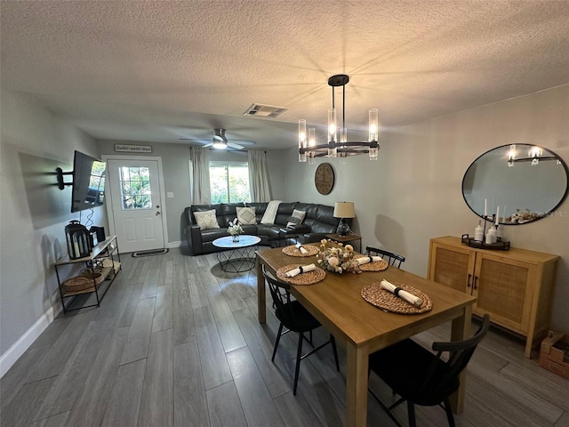 dining room with visible vents, baseboards, wood finished floors, and a textured ceiling