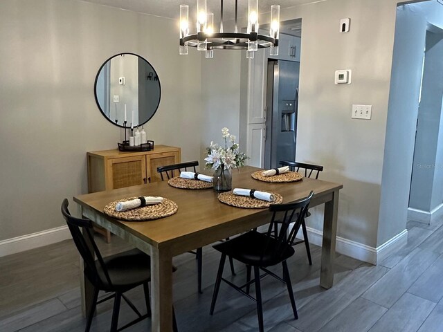 dining room with baseboards, a notable chandelier, and wood finished floors