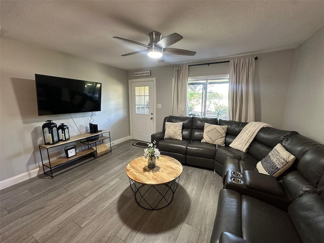 living area with baseboards, a ceiling fan, wood finished floors, and a textured ceiling