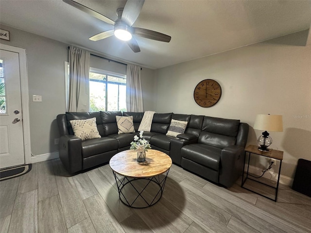 living room featuring light wood-type flooring, baseboards, and a ceiling fan