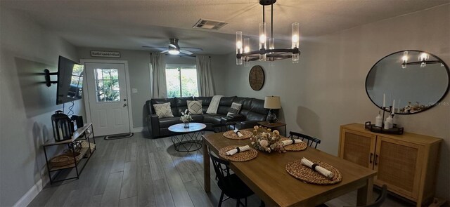dining space with visible vents, ceiling fan with notable chandelier, baseboards, and wood finished floors