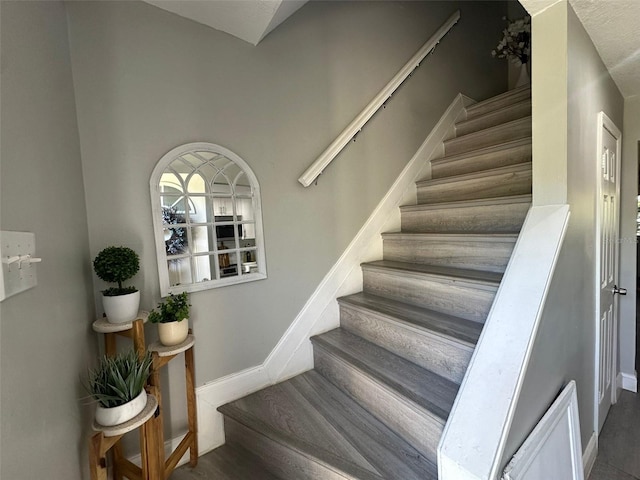 stairs with wood finished floors and baseboards