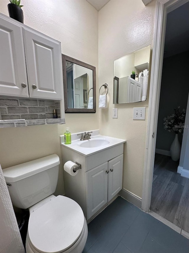 bathroom featuring tile patterned flooring, toilet, vanity, and baseboards
