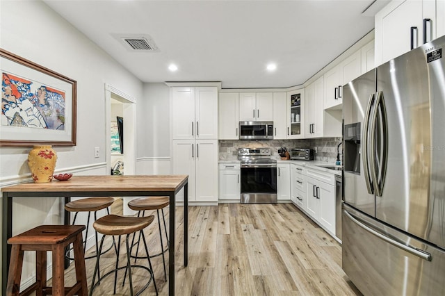 610 N Woodlynne Ave, Tampa, FL 33609 - kitchen with light wood-type flooring, white cabinets, stainless steel appliances, and visible vents