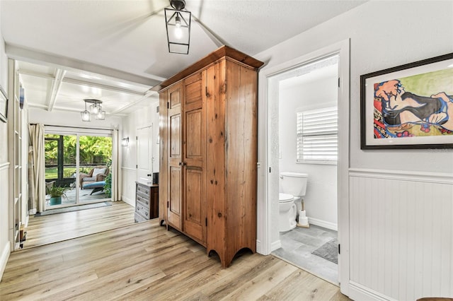 610 N Woodlynne Ave, Tampa, FL 33609 - hallway featuring coffered ceiling, light wood-style flooring, baseboards, beamed ceiling, and an inviting chandelier