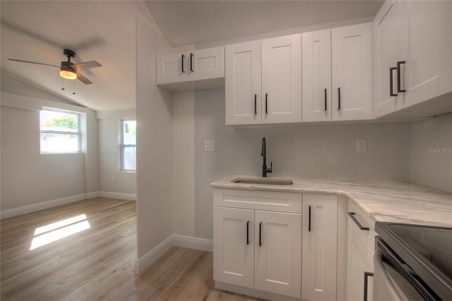 610 N Woodlynne Ave, Tampa, FL 33609 - kitchen featuring ceiling fan, white cabinetry, a sink, light wood-style floors, and vaulted ceiling
