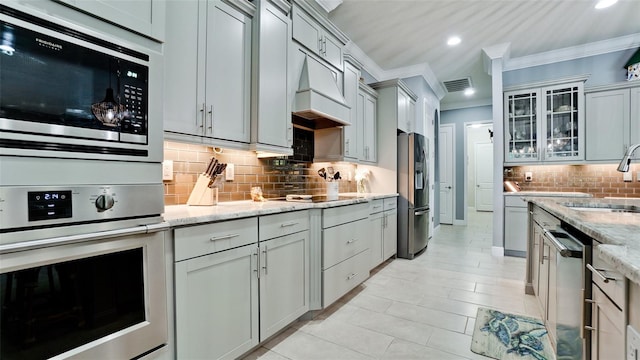 16612 5th Ave E, Bradenton, FL 34212 - kitchen with stainless steel appliances, ornamental molding, decorative backsplash, recessed lighting, and glass insert cabinets