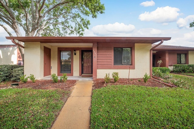 ranch-style house featuring stucco siding and a front lawn