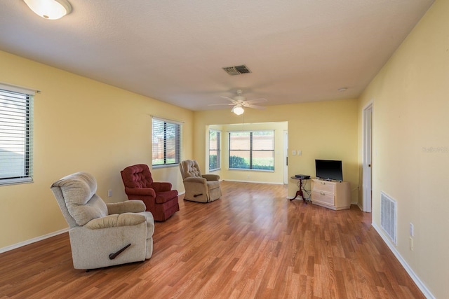 sitting room featuring baseboards, visible vents, light wood-style floors, and ceiling fan