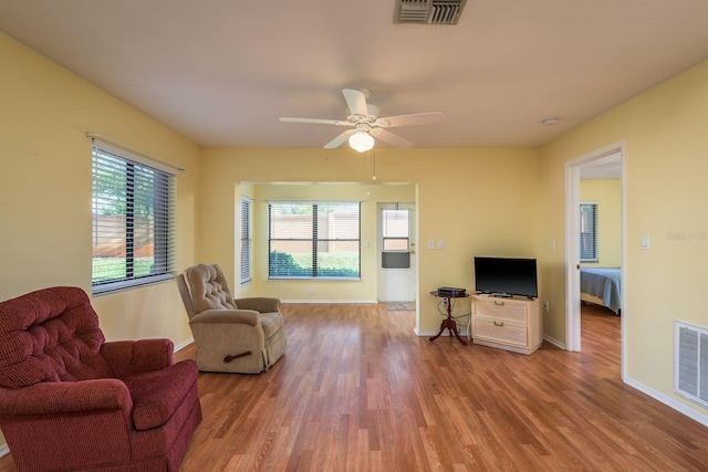 living area with wood finished floors, baseboards, ceiling fan, and visible vents