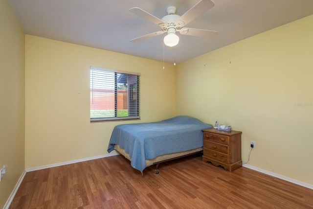 bedroom featuring baseboards, wood finished floors, and ceiling fan
