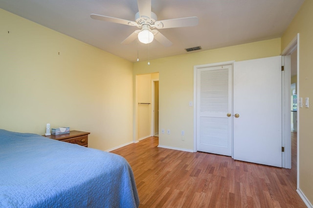 bedroom with a closet, visible vents, baseboards, ceiling fan, and light wood-type flooring