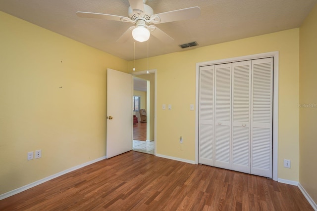 unfurnished bedroom with visible vents, baseboards, a closet, and wood finished floors