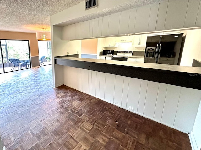 kitchen with a peninsula, black fridge with ice dispenser, visible vents, electric stove, and under cabinet range hood