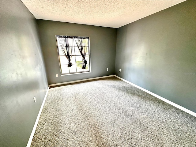 carpeted spare room with a textured ceiling and baseboards