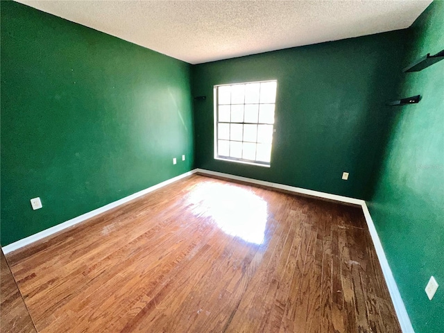 unfurnished room featuring baseboards, a textured ceiling, and wood finished floors