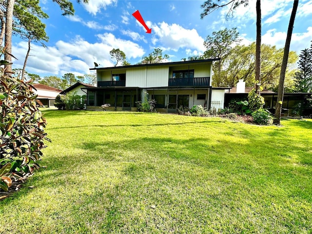 back of property with a yard, a sunroom, and a balcony