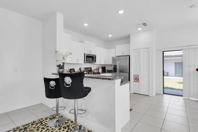 8299 Crescent Oaks Dr, New Port Richey, FL 34655 - kitchen featuring visible vents, a peninsula, a breakfast bar, stainless steel appliances, and white cabinetry