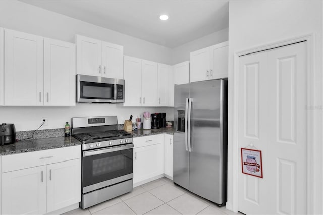 8299 Crescent Oaks Dr, New Port Richey, FL 34655 - kitchen with white cabinets, stainless steel appliances, dark stone countertops, and light tile patterned floors