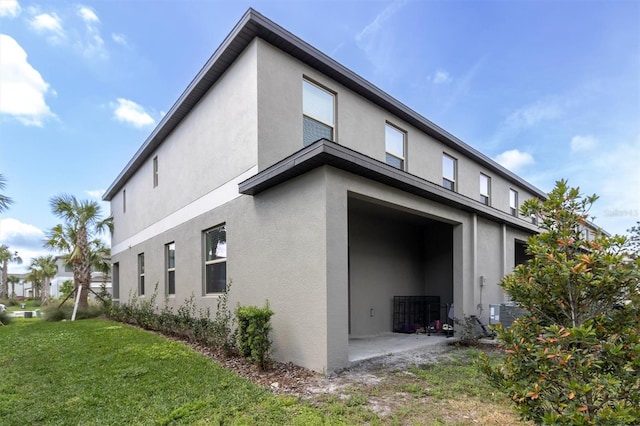 8299 Crescent Oaks Dr, New Port Richey, FL 34655 - view of home's exterior with central AC, stucco siding, and a lawn
