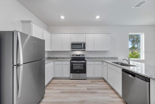 385 Begonia Ct, Poinciana, FL 34759 - kitchen with stainless steel appliances, a sink, white cabinetry, light stone countertops, and recessed lighting