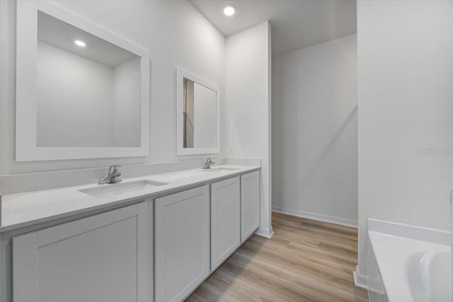 385 Begonia Ct, Poinciana, FL 34759 - bathroom featuring double vanity, wood finished floors, a tub, baseboards, and recessed lighting