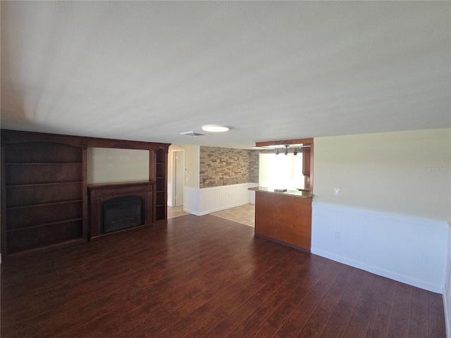 5130 Tilson Dr, New Port Richey, FL 34652 - unfurnished living room featuring built in shelves, a wainscoted wall, hardwood / wood-style flooring, visible vents, and a fireplace