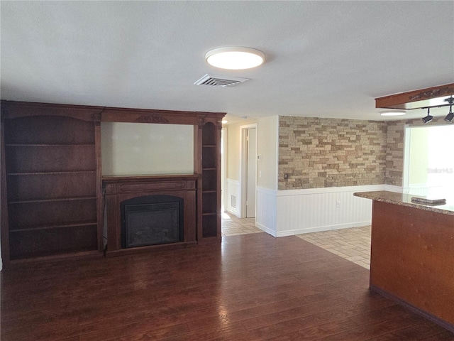 5130 Tilson Dr, New Port Richey, FL 34652 - unfurnished living room featuring a fireplace, visible vents, wainscoting, and wood finished floors