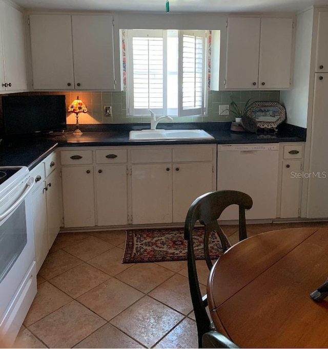 kitchen featuring white appliances, dark countertops, decorative backsplash, and a sink