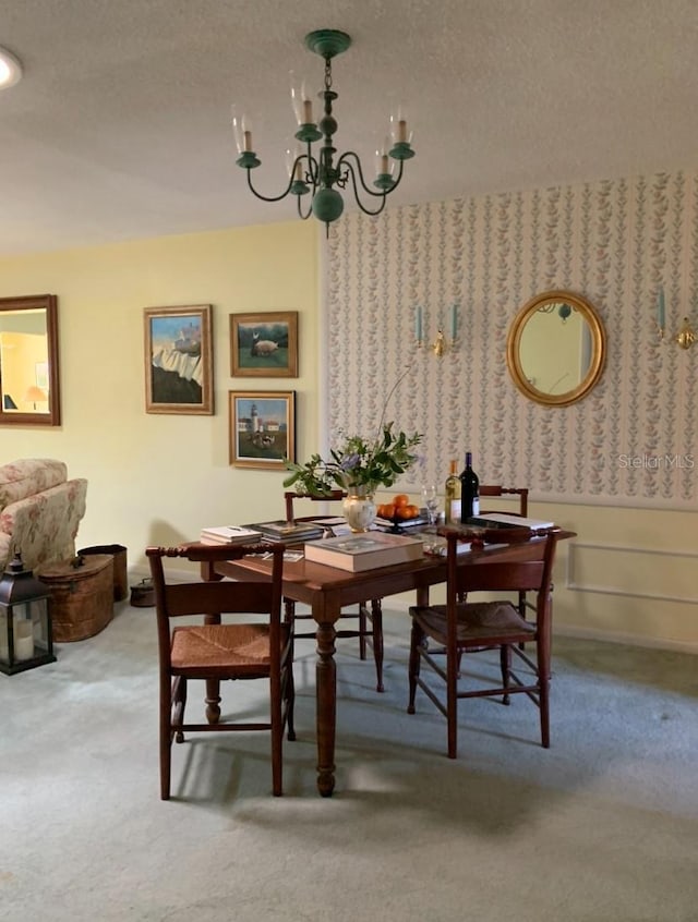 carpeted dining area with a textured ceiling and a chandelier