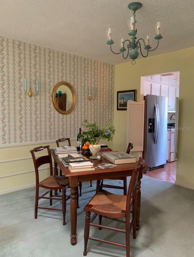 dining area with light carpet, a textured ceiling, light tile patterned floors, wallpapered walls, and an inviting chandelier