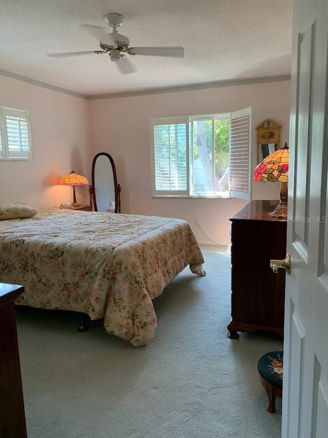 carpeted bedroom featuring a textured ceiling, multiple windows, and a ceiling fan