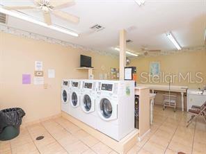 community laundry room with tile patterned floors, washing machine and clothes dryer, and ceiling fan