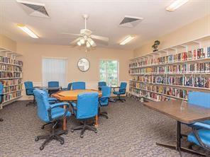 carpeted home office featuring ceiling fan, visible vents, and bookshelves