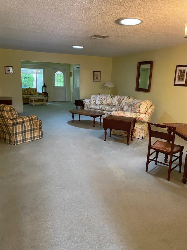 living room featuring visible vents, carpet floors, and a textured ceiling