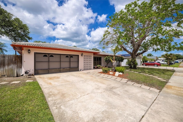 view of front of property with stucco siding, an attached garage, a tiled roof, concrete driveway, and fence
