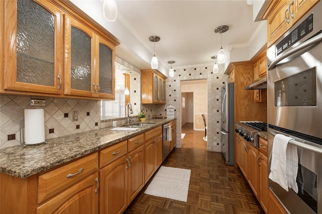 kitchen with a sink, crown molding, stainless steel appliances, glass insert cabinets, and brown cabinets