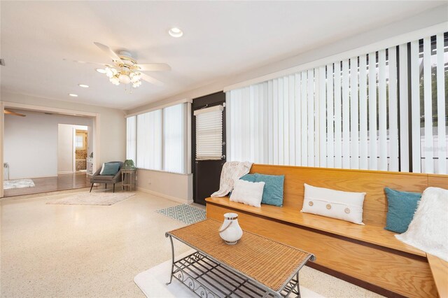 living area with a ceiling fan, recessed lighting, baseboards, and speckle patterned floor