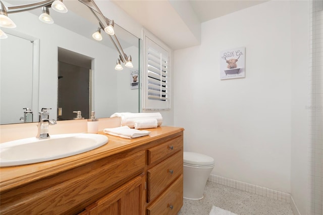 bathroom featuring speckled floor, toilet, vanity, and baseboards