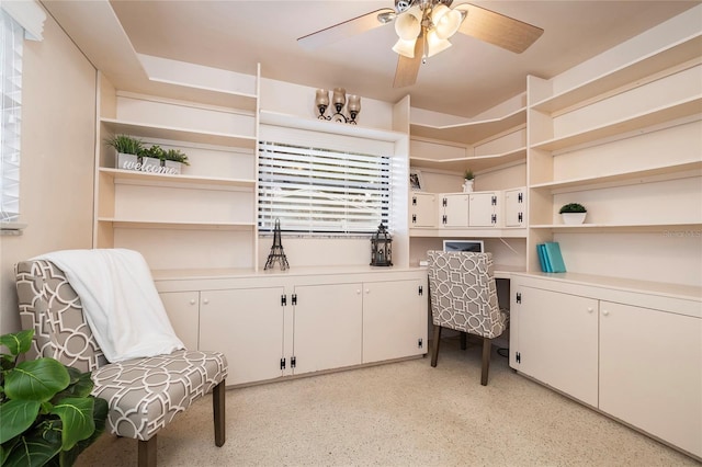 office with a ceiling fan and dark aggregate flooring