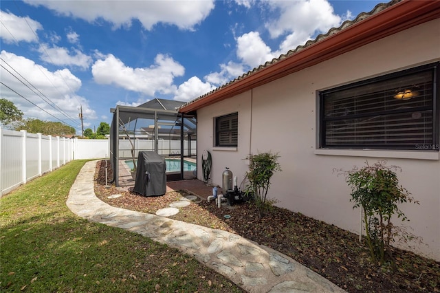 view of yard with a swimming pool, glass enclosure, and a patio area