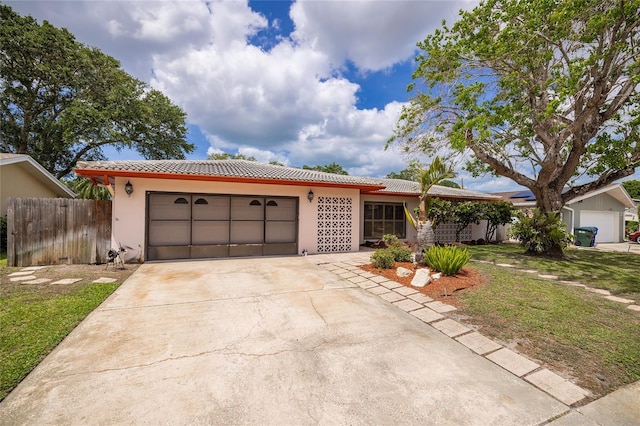 view of front facade featuring a garage, a tile roof, stucco siding, fence, and concrete driveway